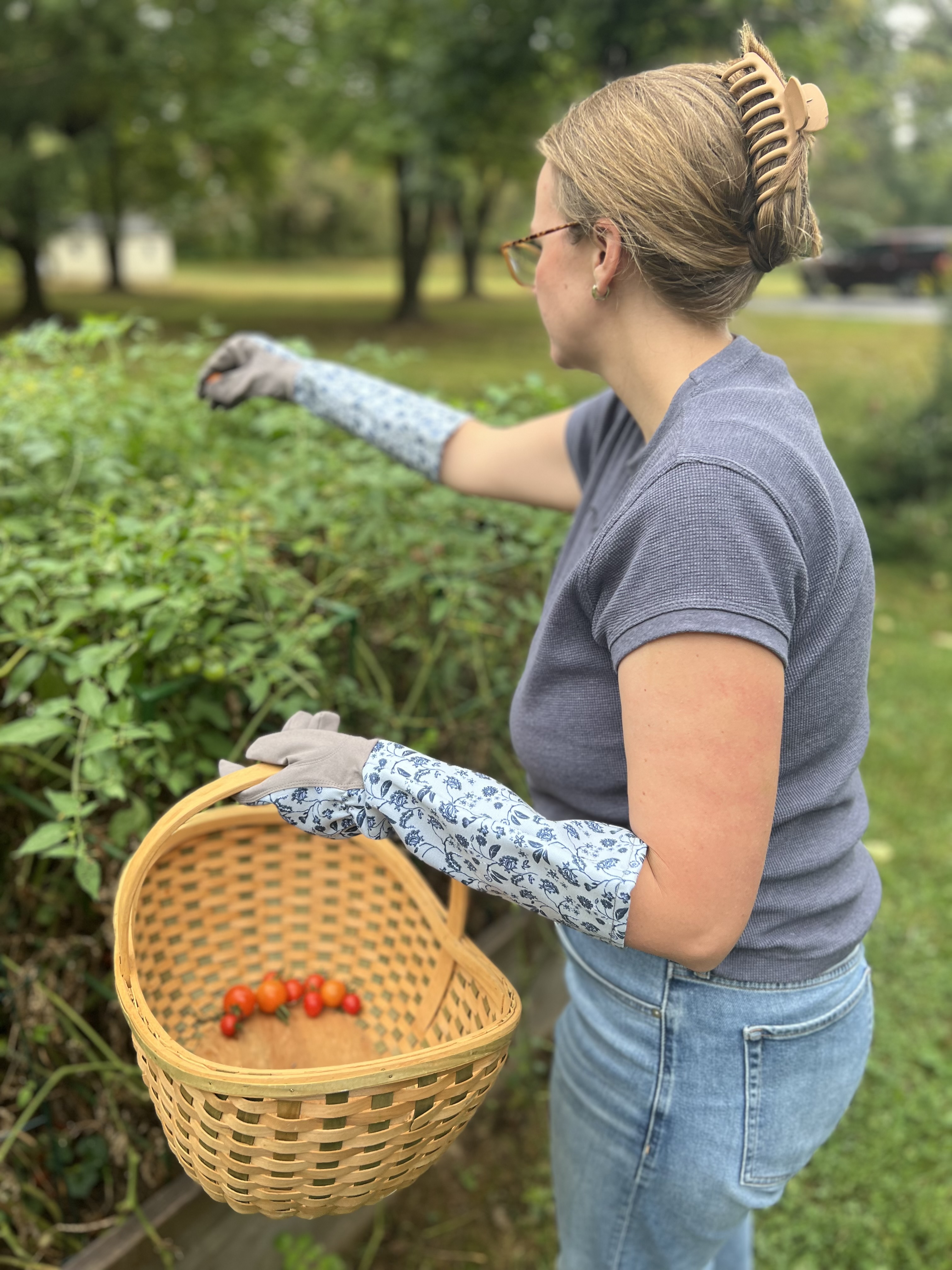 woman wearing gardening gloves picking tomatoes