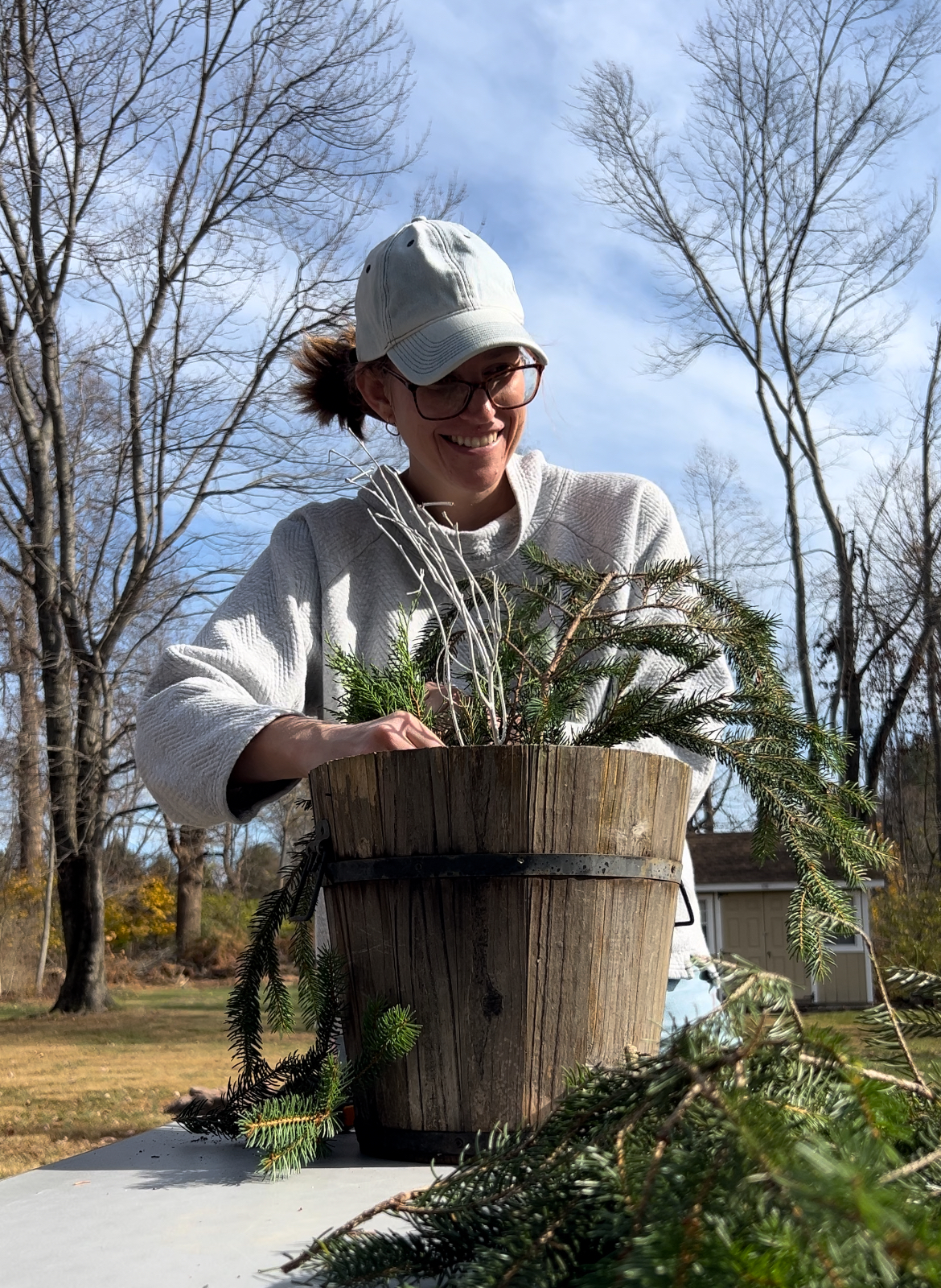 woman creating a winter porch pot with evergreen and pine clippings