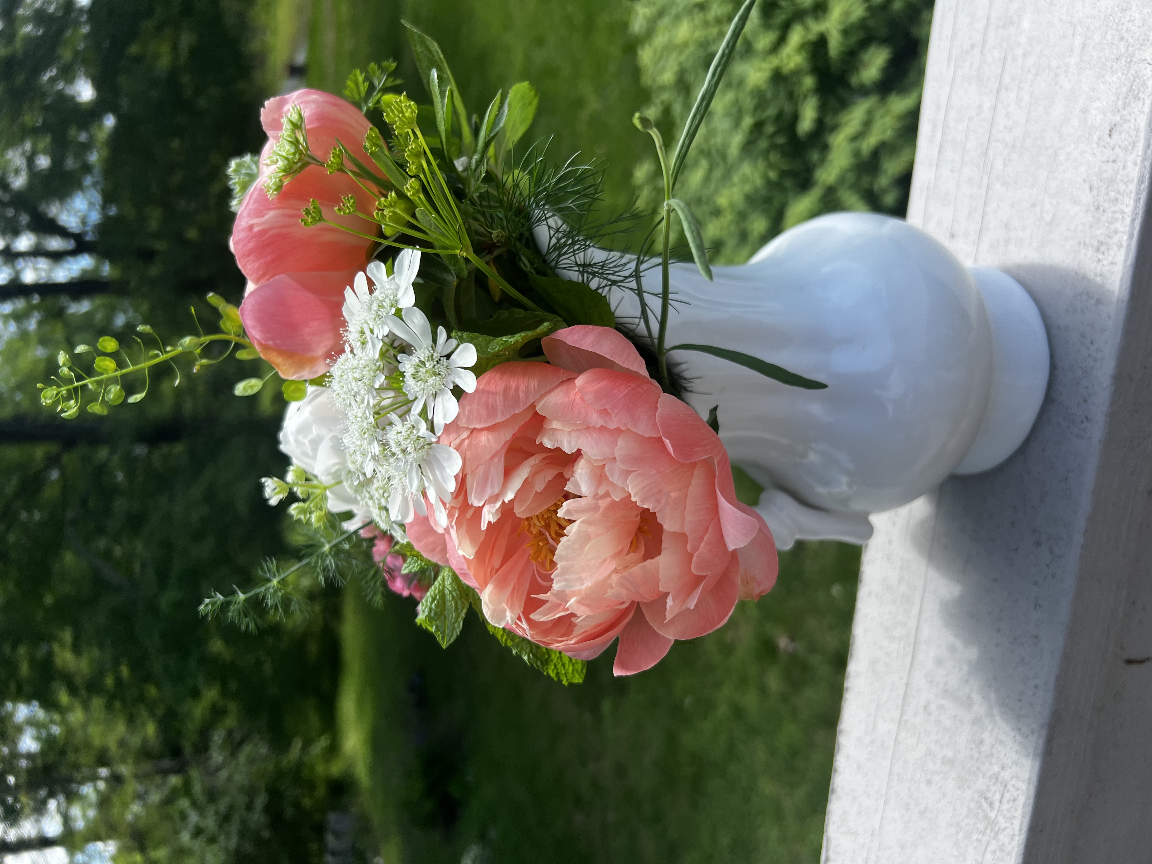 Peony flower bouquet of local flowers in a white ceramic pottery pitcher